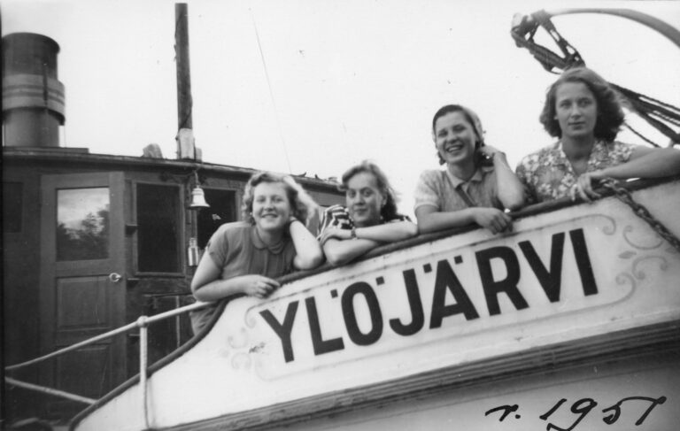 Kolme naista kuvattu laivan reunan yli. Laivassa lukee Ylöjärvi. Mustavalkoinen.