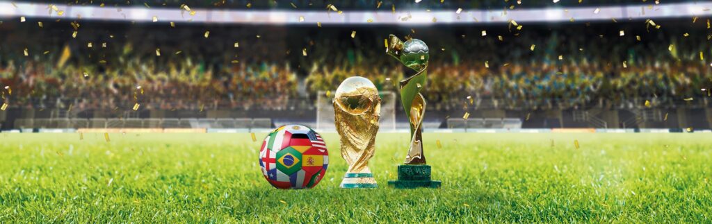 Trophies and a football on a green grass in a stadium.